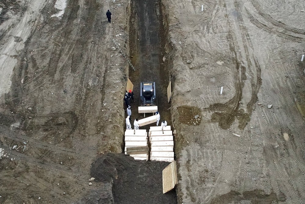 Trabalhadores enterram corpos em uma vala em Hart Island, no bairro do Bronx, em Nova York. — Foto: AP Photo/John Minchillo
