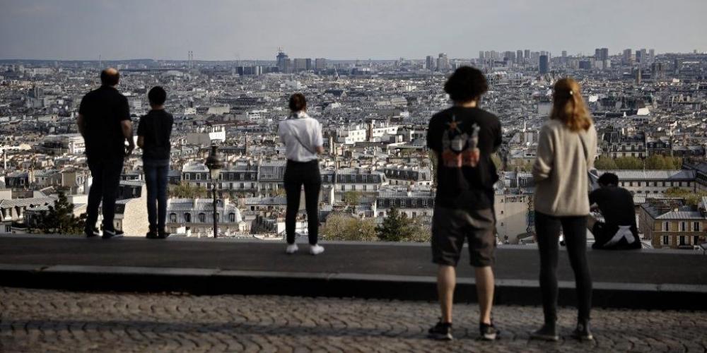 Pessoas olham para a vista panorâmica no distrito turístico de Montmartre, em Paris, no 27º dia de isolamento restrito | Foto: Thomas Coex / AFP / CP