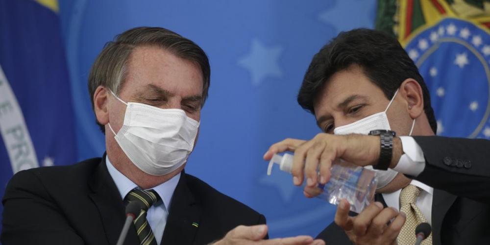 O presidente da República, Jair Bolsonaro (e), recebe álcool em gel do ministro da Saúde, Luiz Henrique Mandetta, durante entrevista coletiva à imprensa sobre as medidas de combate ao novo coronavírus (Covid-19), no dia 18 de março | Foto: DIDA SAMPAIO/ES